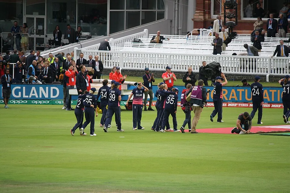 A women's cricket squad gathering together on the outfield. CC0 sample; not Tailor academy photography.